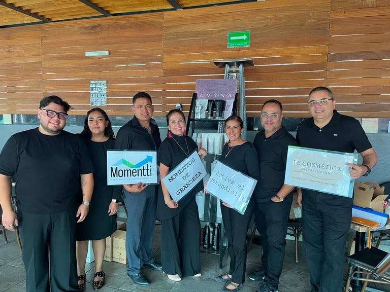 Team of seven people in black shirts holding business signs and awards in a modern wooden-walled office space