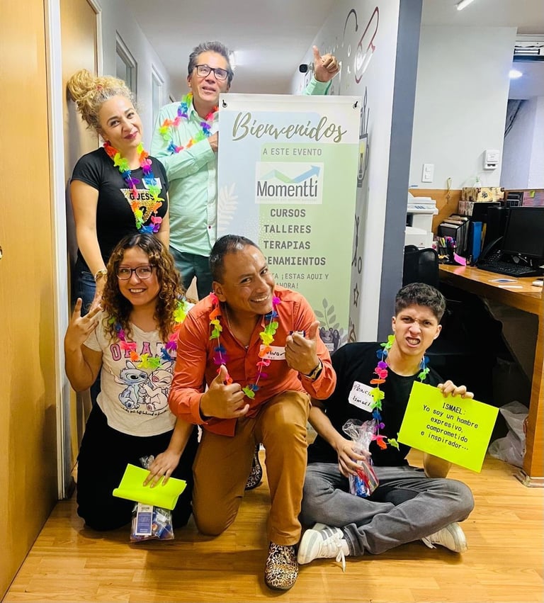 Five people smiling at Momentti event wearing leis, holding neon signs in front of welcome banner