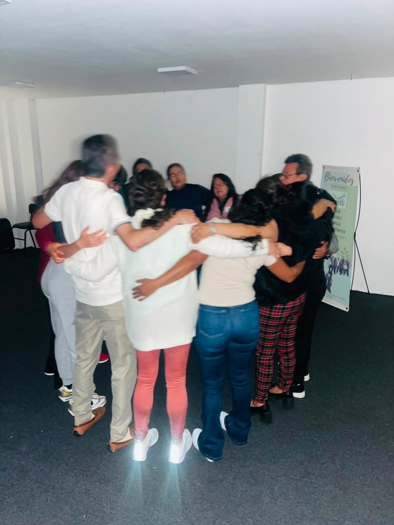 Group of people standing in a circle with arms around each other in a team-building activity indoors