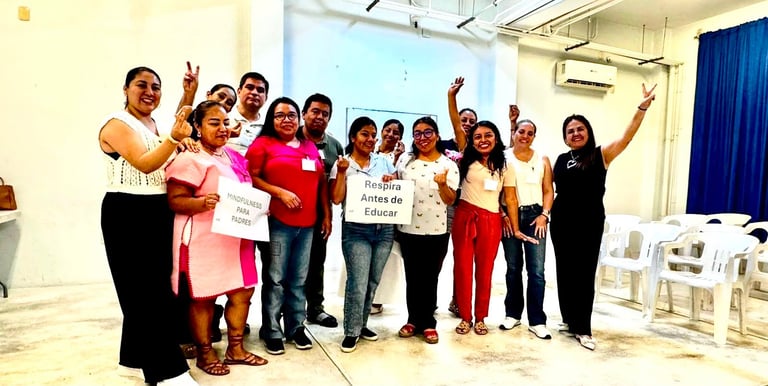 Group of diverse people standing together in a room with raised fists and hands, wearing colorful casual clothing at what appears to be a community gathering or celebration event