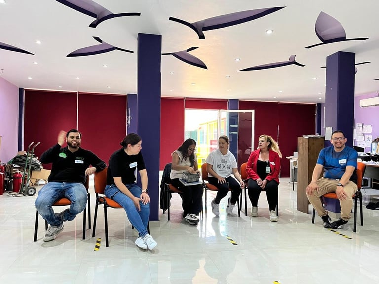 Group of people sitting in a circle during a discussion or meeting in a modern space with red walls and ceiling fans