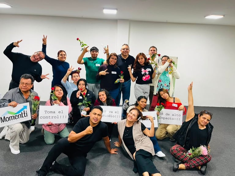 Group of diverse people celebrating indoors, holding signs and trophies, posing together in a classroom or office space