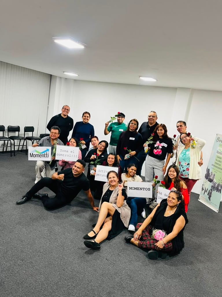 Group of diverse people of various ages posing together indoors, holding Momentos signs, appearing to be at a community event or workshop